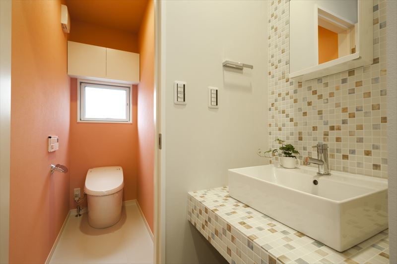 モザイクタイルとオレンジのアクセント壁で楽しいトイレ空間