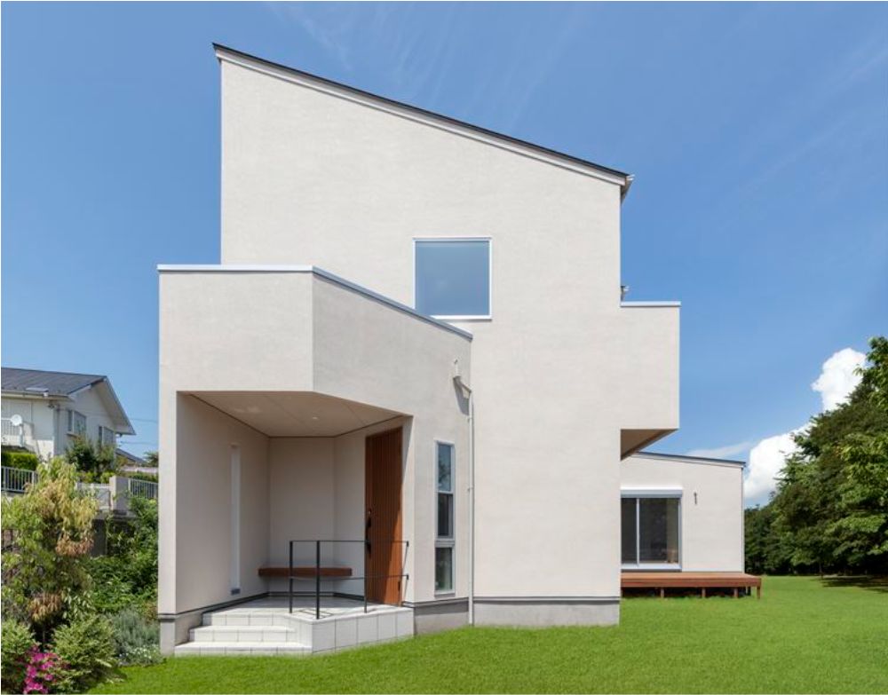 大きな庭白の塗壁と片流れ屋根のモダンな外観
